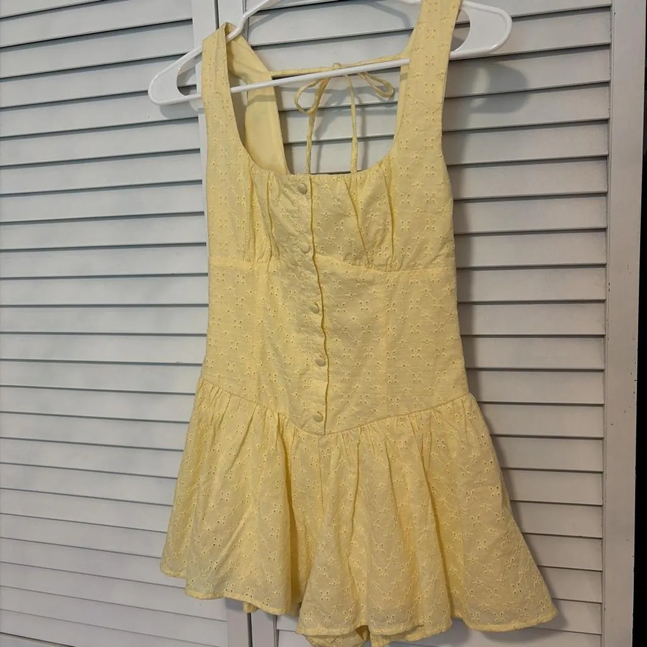 Original phone photo of a yellow romper on a hanger